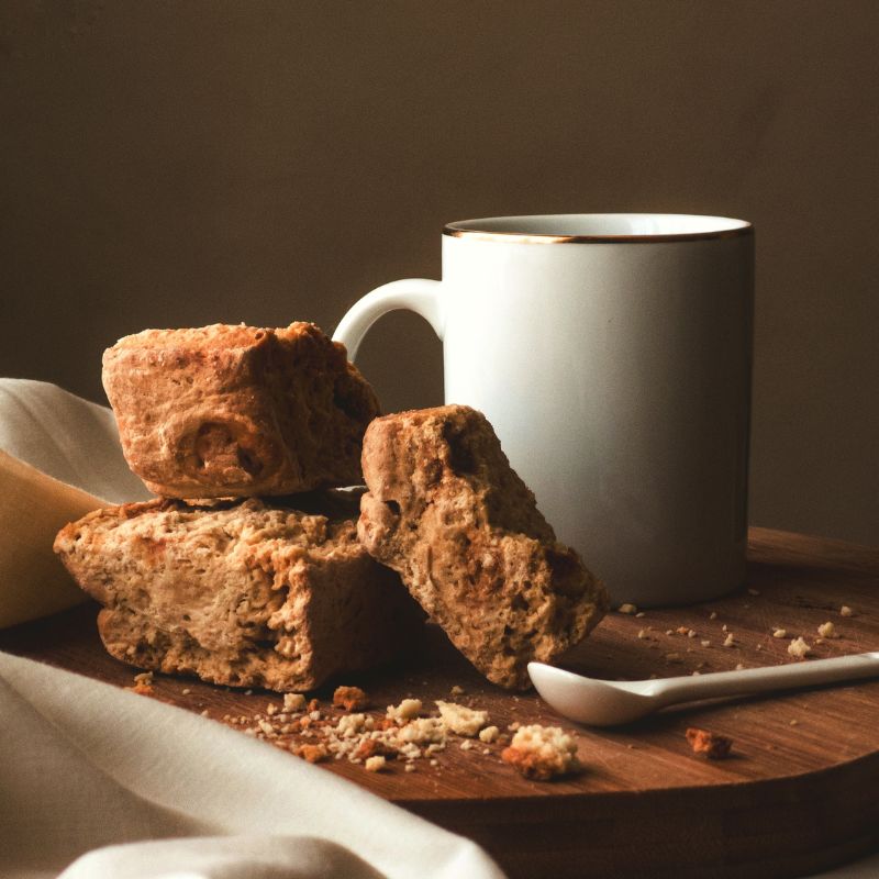 Traditional South African rusks on a wooden board beside a ceramic mug and spoon – a wholesome tea-time snack enjoyed across the UK.